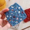a person holding a crochet granny square