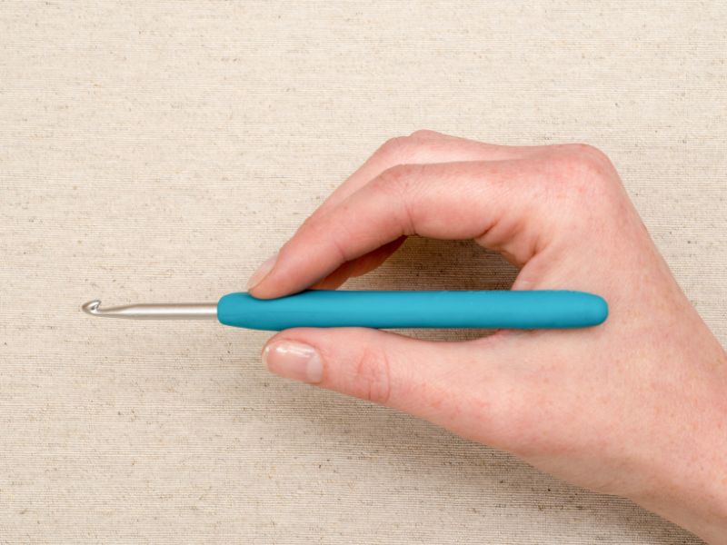 a person holding a blue crochet hook