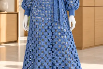 Denim blue lattice crochet dress on mannequin featuring open square grid pattern, balloon sleeves, and tied waist belt