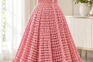 Rose pink crochet dress with V-neck, filet openwork bodice, flared skirt, and layered rose flower hem on dress form