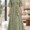 Sage green crocheted mesh dress with V-neckline, daisy appliqués along vertical bands, elbow sleeves, and tie waist worn by woman in bright room