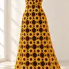 Golden yellow crocheted sunflower maxi dress with chocolate brown centers displayed on a white dress form in soft natural light